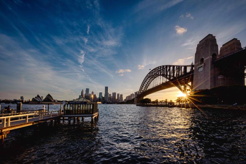 A bridge crossing a body of water at sunset in Sydney, Australia