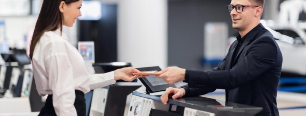 Friendly woman staff taking passport from passenger at airport check in