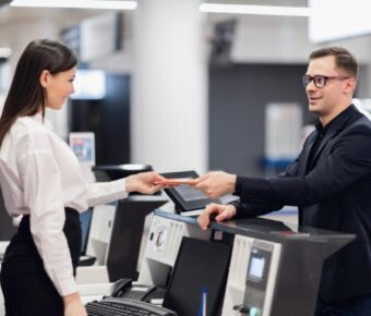 Friendly woman staff taking passport from passenger at airport check in