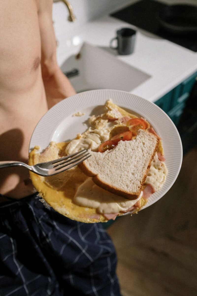 Shirtless man eating Plate with Croque Madame Sandwich