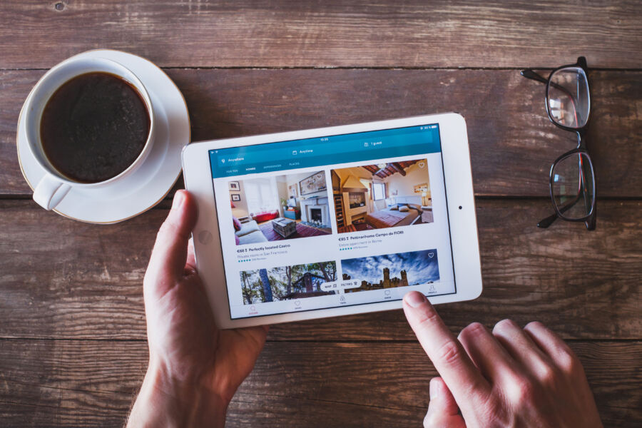 Individual booking an apartment through the Airbnb app displayed on a tablet screen