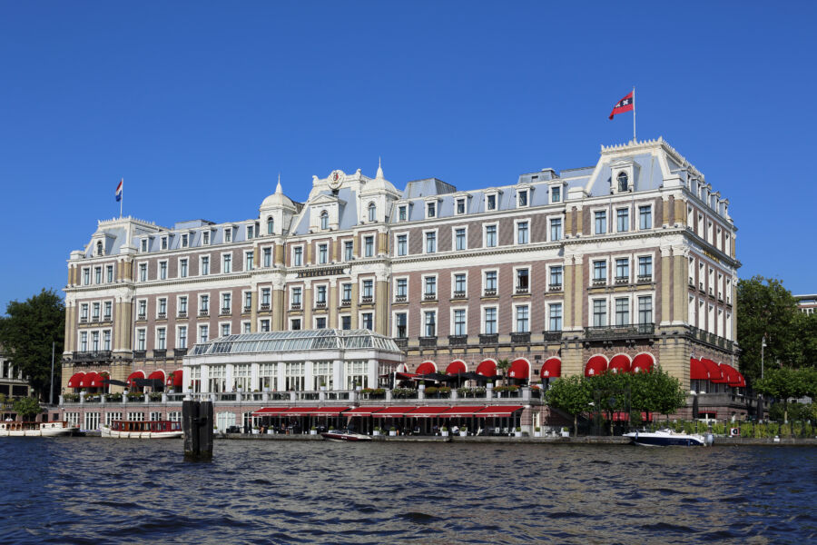 Exterior view of Amstel Hotel in Amsterdam with a skyline backdrop, showcasing its architectural elegance and surrounding cityscape