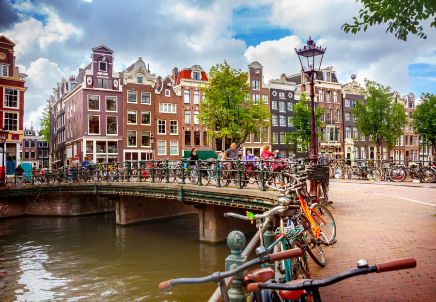 Scenic view of an Amsterdam canal, featuring traditional Dutch architecture and serene waters reflecting the sky