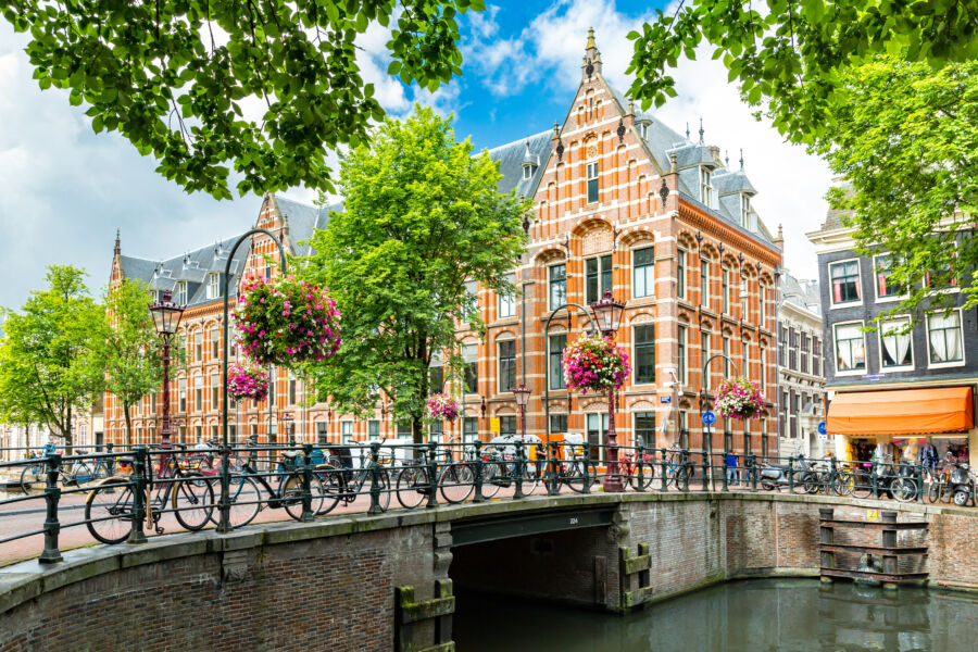 Scenic Amsterdam canal view featuring the 17th-century Dutch East India Company headquarters, now part of the University of Amsterdam