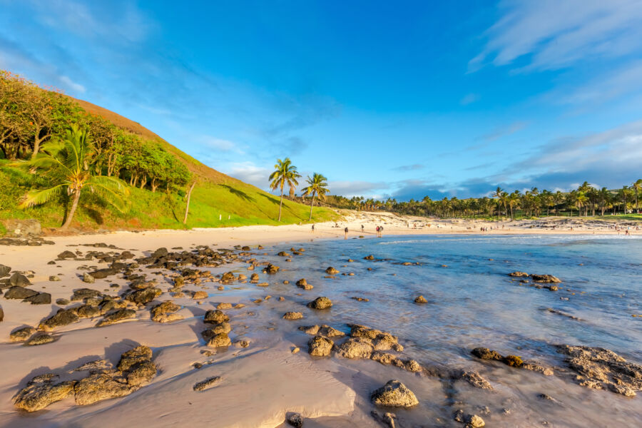 Panoramic view of Anakena Beach, showcasing its white sands, clear waters, and iconic moai statues under a bright sky