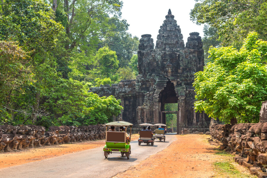 Vibrant Tuk Tuk ride in Angkor, Cambodia, surrounded by lush greenery, offering a unique transportation experience