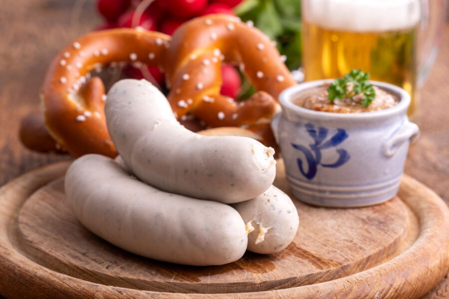 Close-up of Bavarian Weisswurst, showcasing the smooth, pale texture of the white sausages on a wooden cutting board