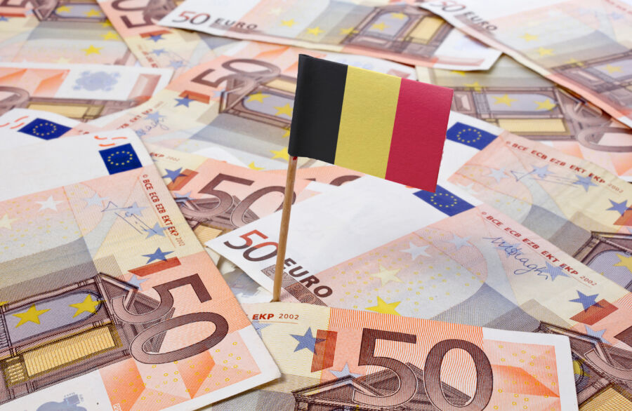 Flag of Belgium prominently displayed among a stack of 50 Euro banknotes