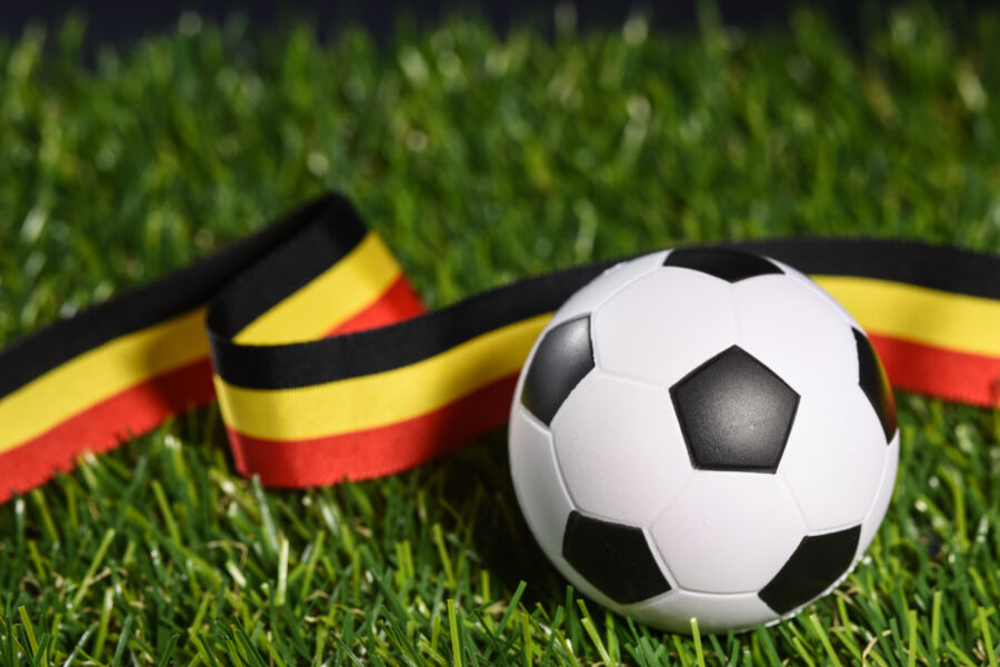 Belgium flag and a football resting on green grass, symbolizing the nation's passion for soccer