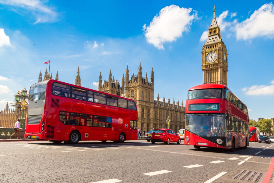 Big Ben Clock Tower and Westminster Bridge stands tall as a London buses passes by