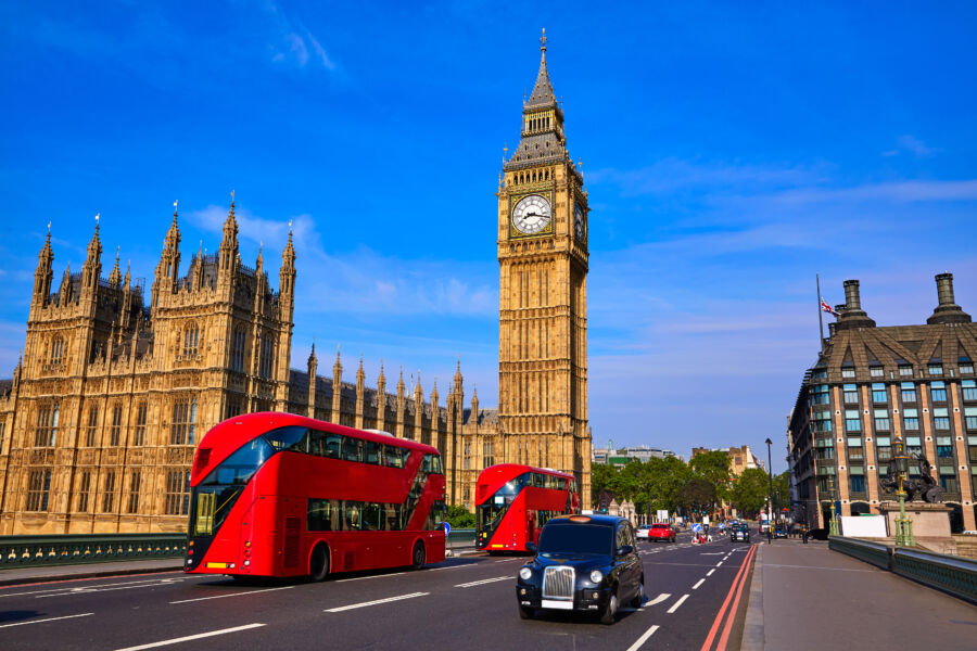 Big Ben Clock Tower stands tall as a London bus passes by