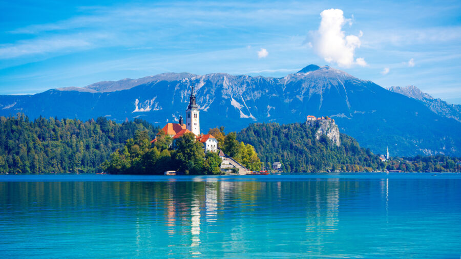 Scenic view of Lake Bled in Slovenia, featuring a picturesque island church and surrounding mountains, ideal for tourism