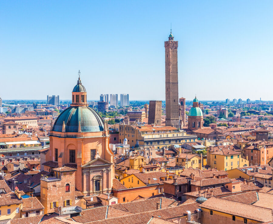 The cityscape of Bologna featuring its iconic towers, terracotta rooftops, and bustling streets