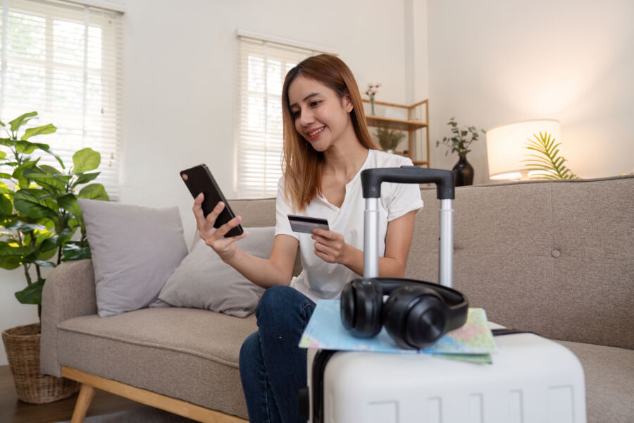 Asian woman using credit card booking flight tickets and hotel at home. Planning a trip and online booking, Summer vacation concept