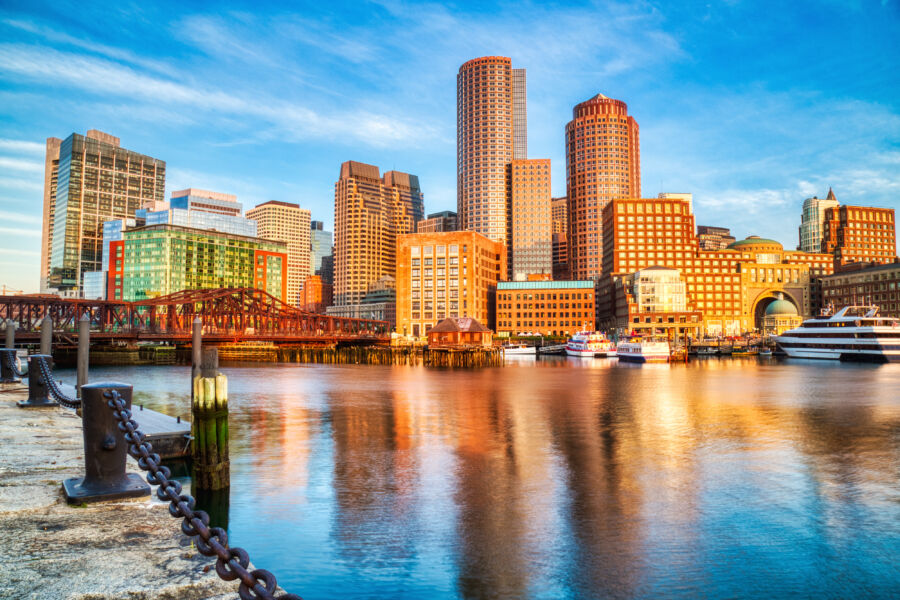 The Boston skyline illuminated by sunrise, showcasing the Financial District and Boston Harbor in a serene morning atmosphere