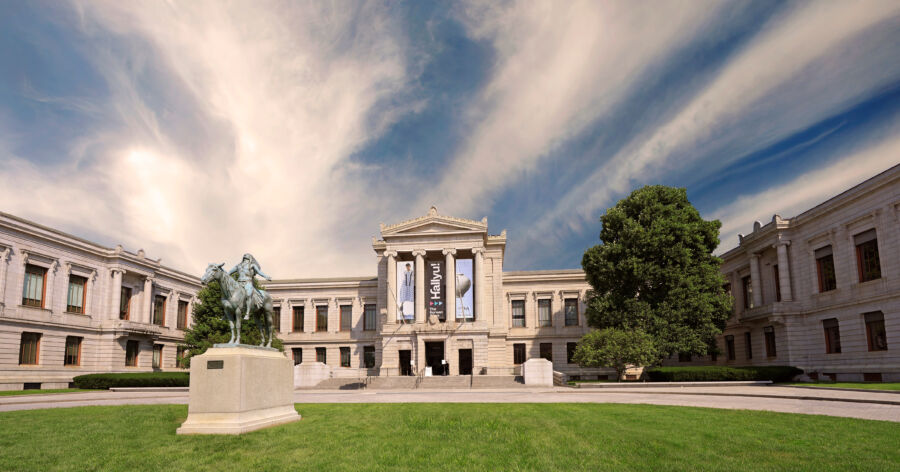 The Boston Museum of Fine Arts stands majestically under a clear blue sky, showcasing its impressive art collections