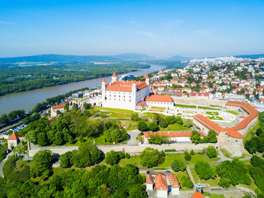 Aerial panoramic view of Bratislava, Slovakia, showcasing the city's skyline, river, and historic architecture