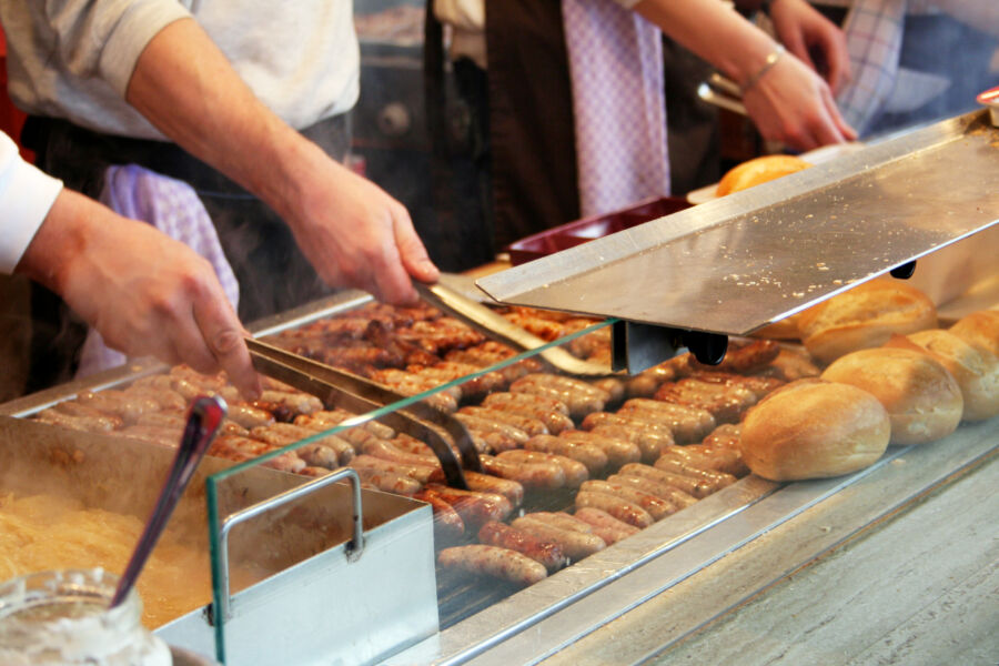 Hot dog stall in Germany showcasing bratwurste being prepared on a grill, with a vibrant atmosphere and eager customers