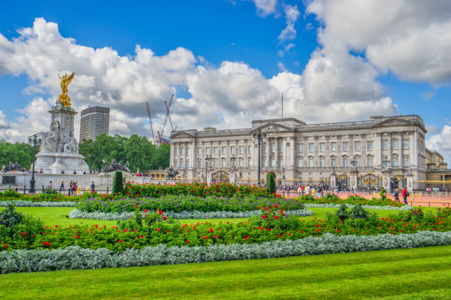 The stunning architecture of Buckingham Palace framed by a beautiful garden, showcasing London's iconic royal residence.