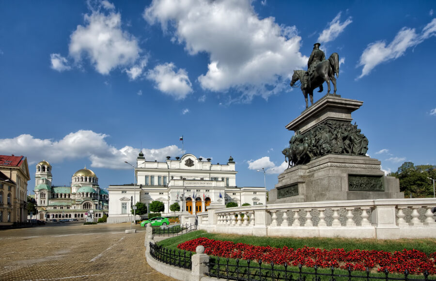 The Bulgarian Parliament building stands prominently in front of the Monument to the Tsar Liberator in Sofia, Bulgaria