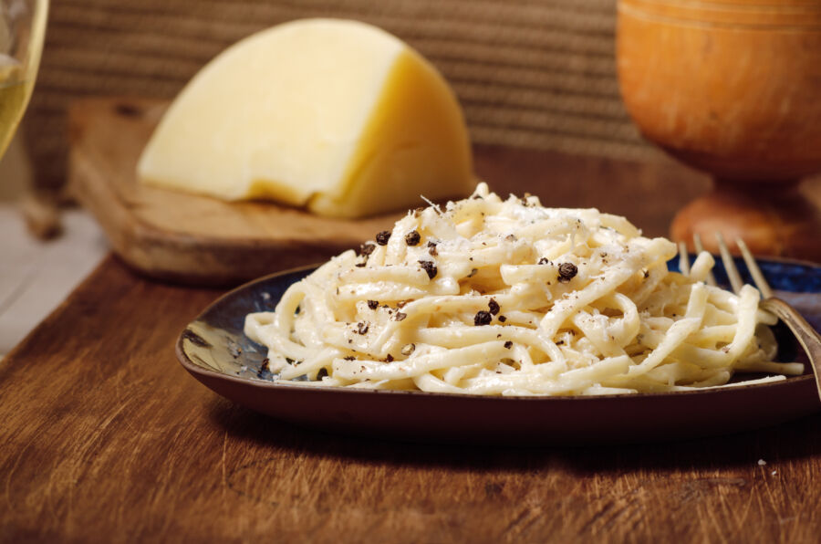 Serving of Cacio e Pepe, showcasing pasta mixed with grated Pecorino Romano cheese and a generous amount of black pepper