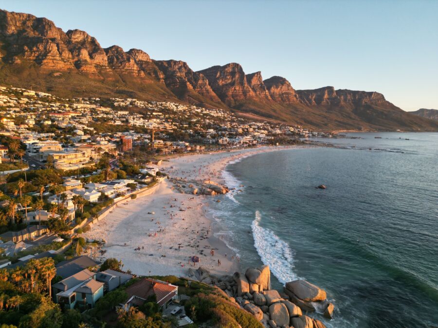 Camps Bay beach bathed in golden hour light, framed by the impressive mountains of Cape Town, South Africa.