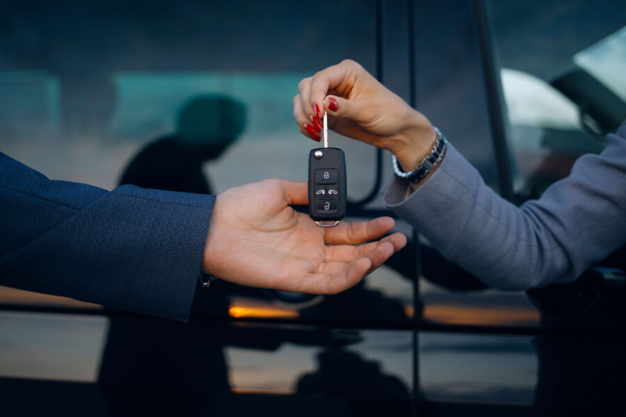 Woman hands car keys to a man, indicating a car rental transaction