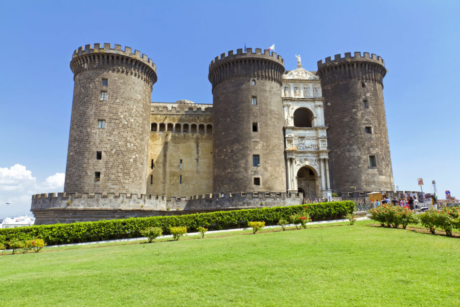 The majestic Castel Nuovo in Naples, Italy, featuring its iconic towers and arched entrance, surrounded by vibrant city life.