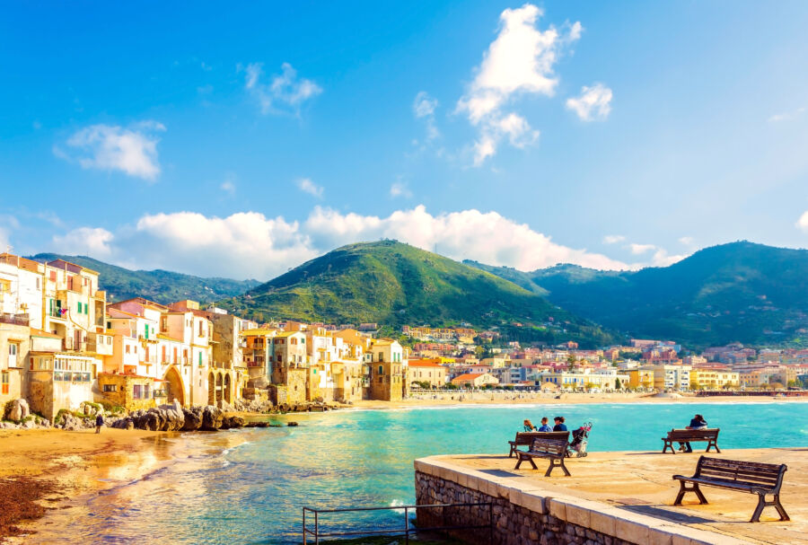 The beach town view of the Cefalu in Sicily, Italy, during the evening, featuring its stunning coastline and historic buildings