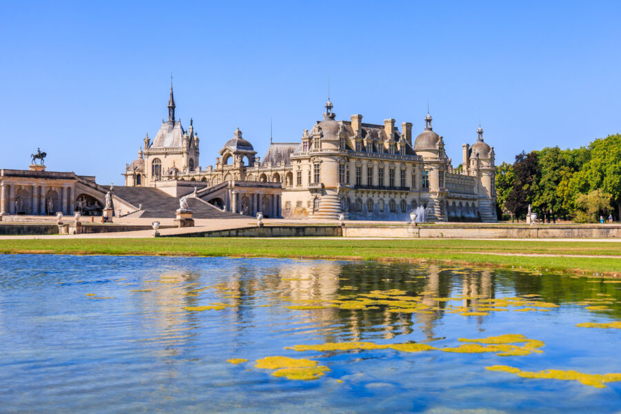 Scenic view of the Chateau de Chantilly from the lush garden, showcasing its stunning architecture and beautiful surroundings