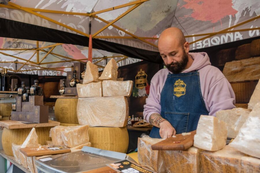 Vibrant cheese market scene featuring artisan vendor, various cheese types, and festive atmosphere.