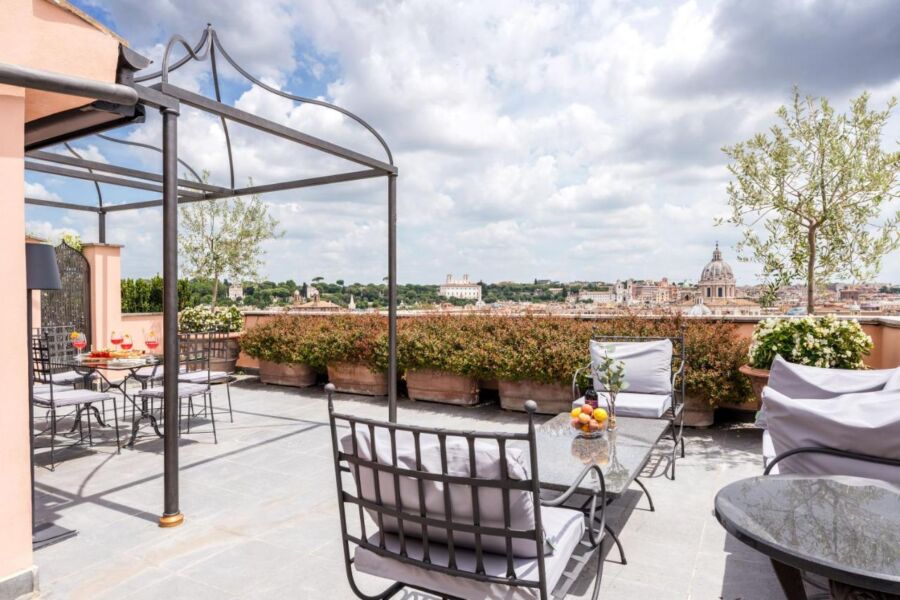 Rooftop terrace in Rome with city views, stylish furniture, and lush greenery.