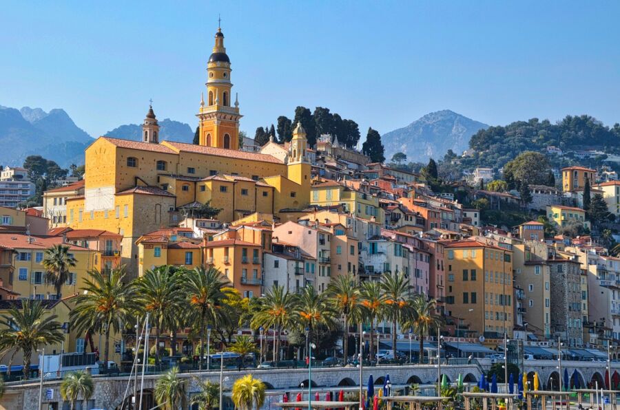 Picturesque Mediterranean coastal town with colorful architecture, marina, palm trees, and serene ambiance.