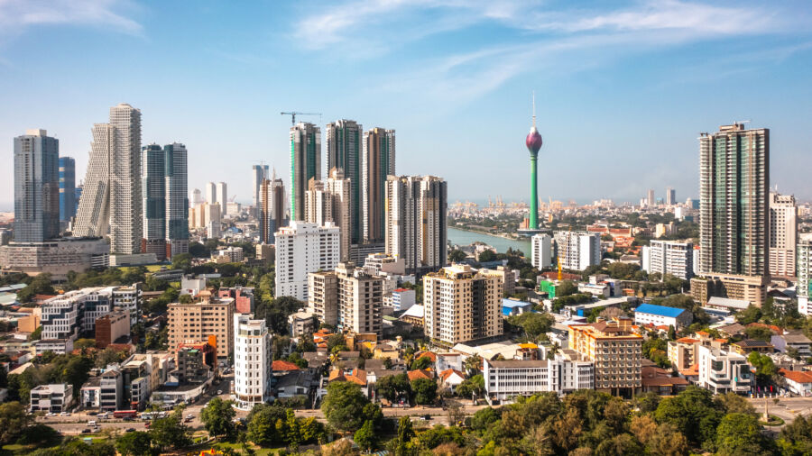 Aerial view of Colombo cityscape under a clear blue sky, showcasing vibrant buildings and lush greenery in Sri Lanka