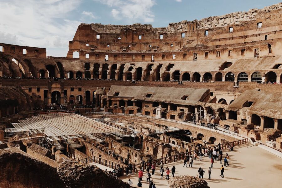 Iconic Roman Colosseum interior with ancient architecture, arches, visitors, and restoration efforts.