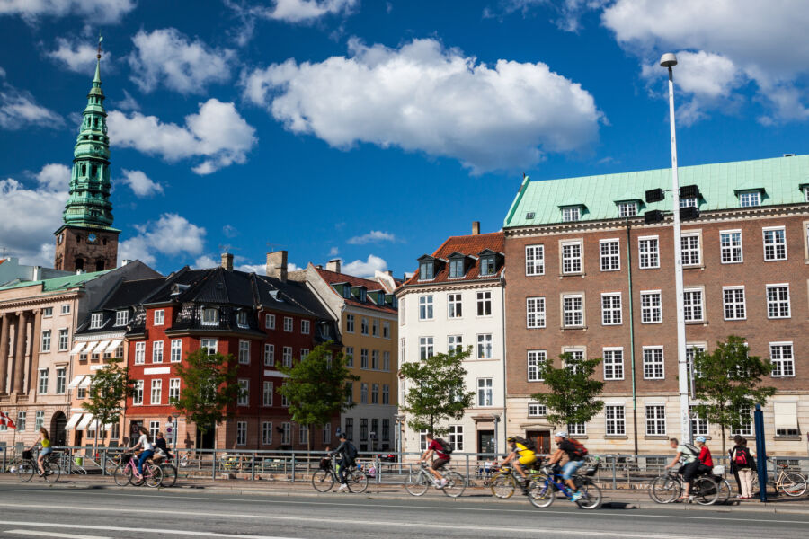 Cyclists riding through the picturesque streets of Copenhagen, Denmark, highlighting the city's commitment to biking as a mode of transport