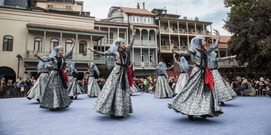 Traditional dancers performing at a cultural festival outdoors with an engaged audience.