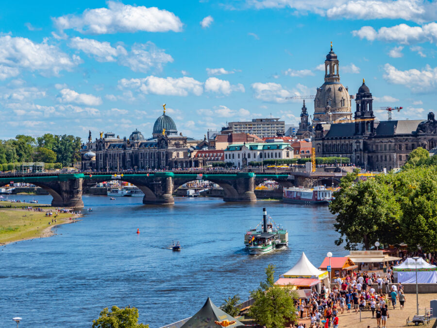 Panoramic view of Dresden, Germany, showcasing historic architecture and the Elbe River under a clear blue sky