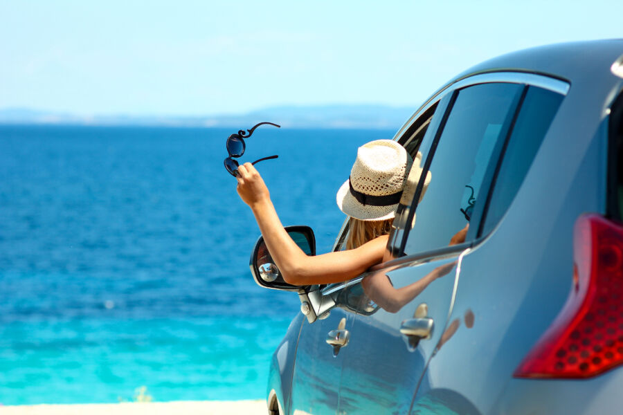 Cheerful driver enjoys a summer day in a car by the sea driving 