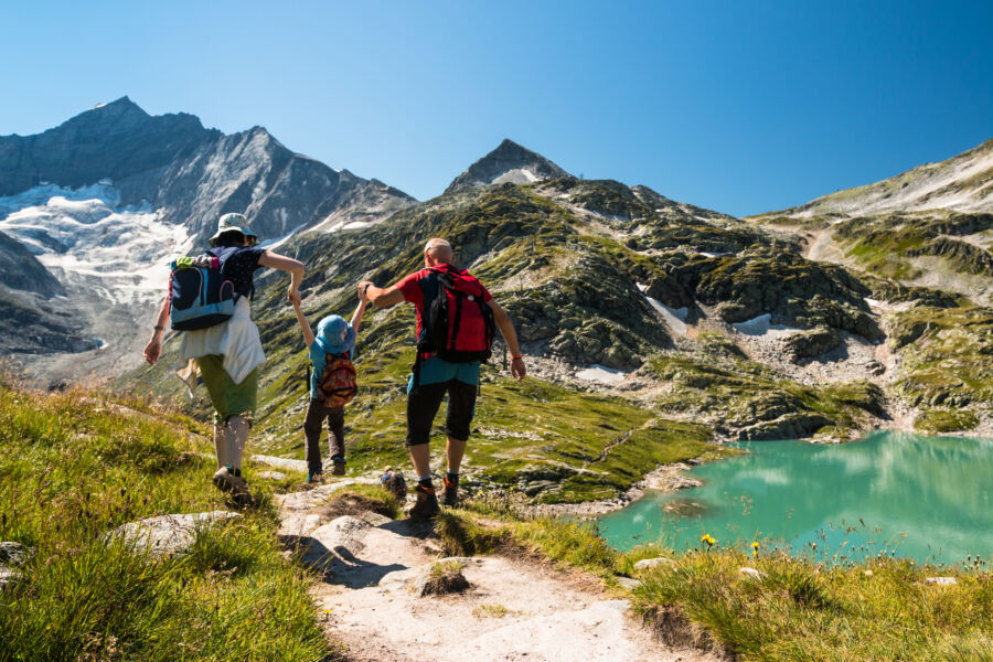 Family with a child enjoys a hiking adventure in the picturesque Austrian Alps during their holiday.