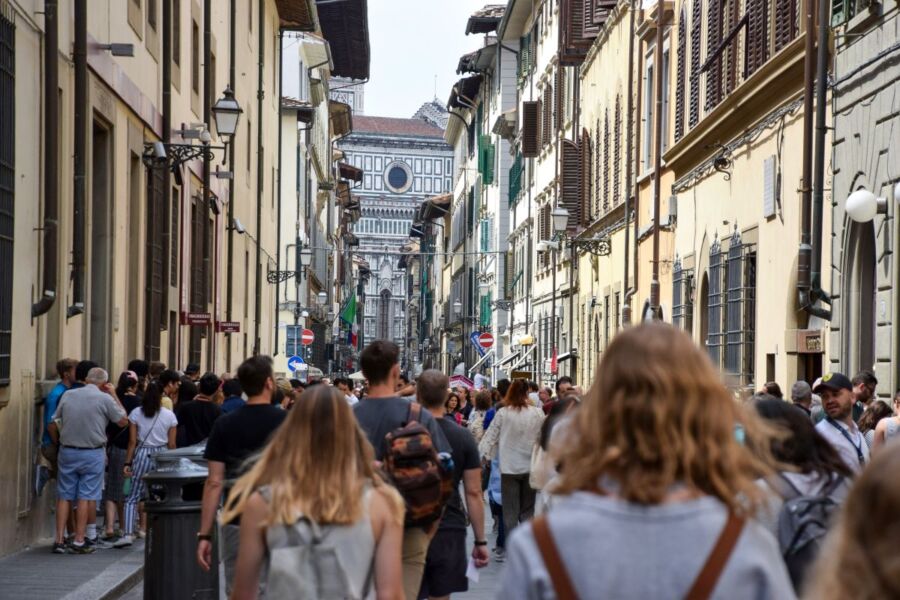 Lively Florence street featuring historic architecture, tourists, and iconic landmark under a clear sky.