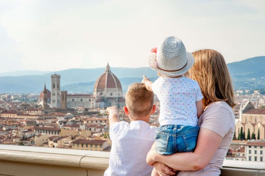 Family enjoys scenic Florence view, featuring Duomo and historic architecture, under sunny skies.