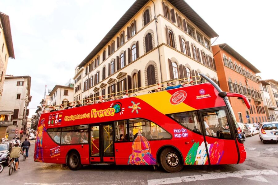 Tourist double-decker bus in Florence, Italy, against historic architecture.