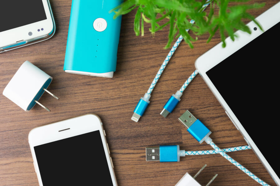 Different gadgets displayed, showcasing charging cables alongside a smartphone and a tablet on a clean background