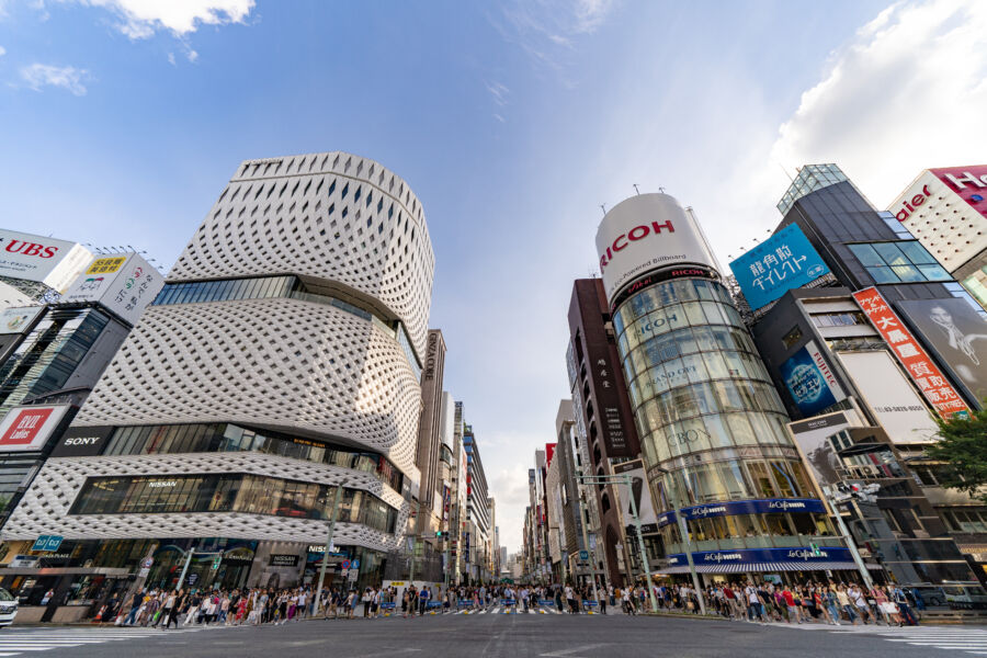 The iconic Ricoh electronic billboard in Ginza, Tokyo, with pedestrians navigating the lively shopping district