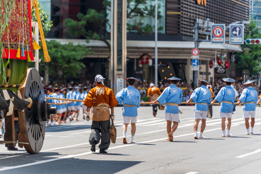 Participants in traditional attire pull a massive wooden float during the Yamaboko Junko procession at the Gion Matsuri Festival