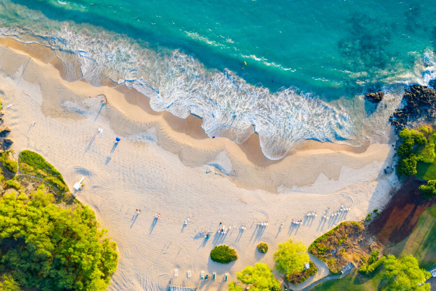 Picturesque scene of Hapuna Beach, located on Hawaii's Big Island, with golden sands and vibrant blue waters under a clear sky