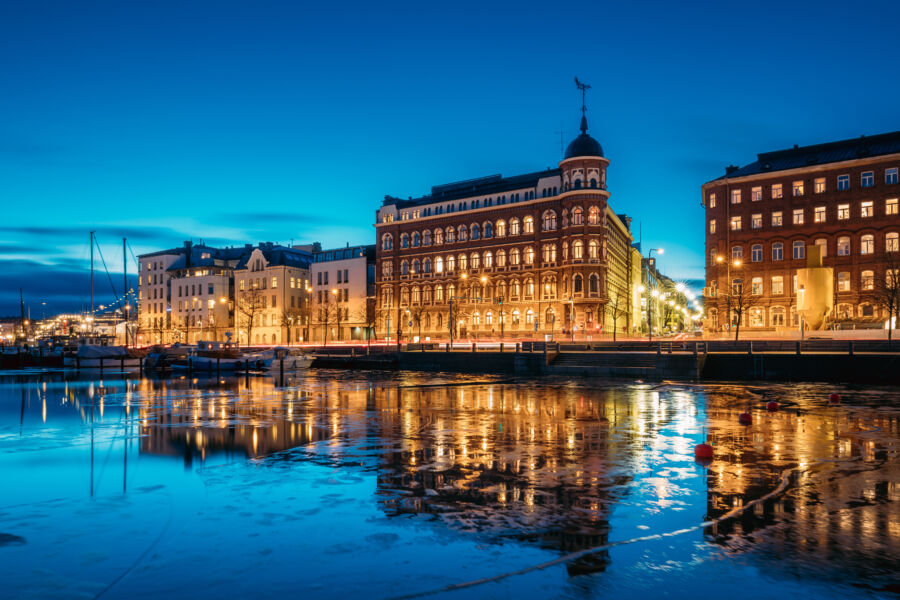 Evening view of Pohjoisranta Street in Helsinki, Finland, illuminated by streetlights and reflecting on the water