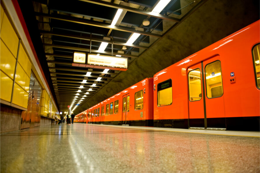 Bright orange Metro train in Helsinki, poised at a station, highlighting the city's modern public transport system