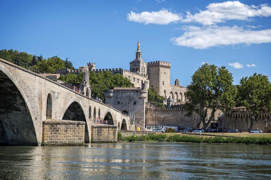 Ancient stone bridge and majestic castle amidst lush greenery and serene waters.